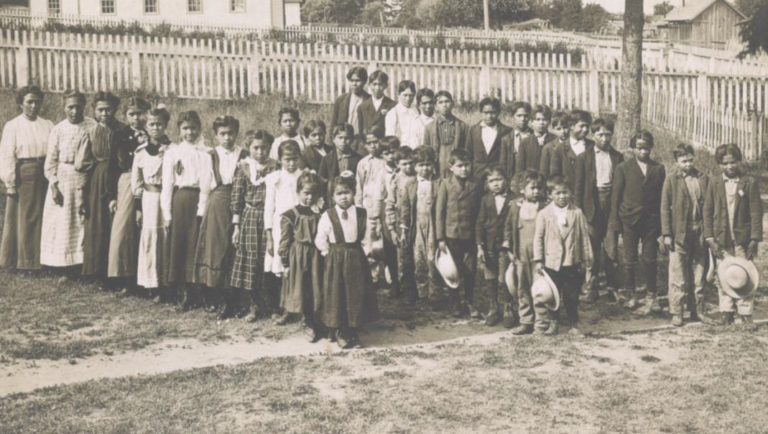 A group photo of Native American children outside a tribal boarding school.