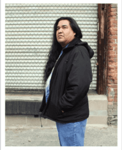 Native man standing in front of a building